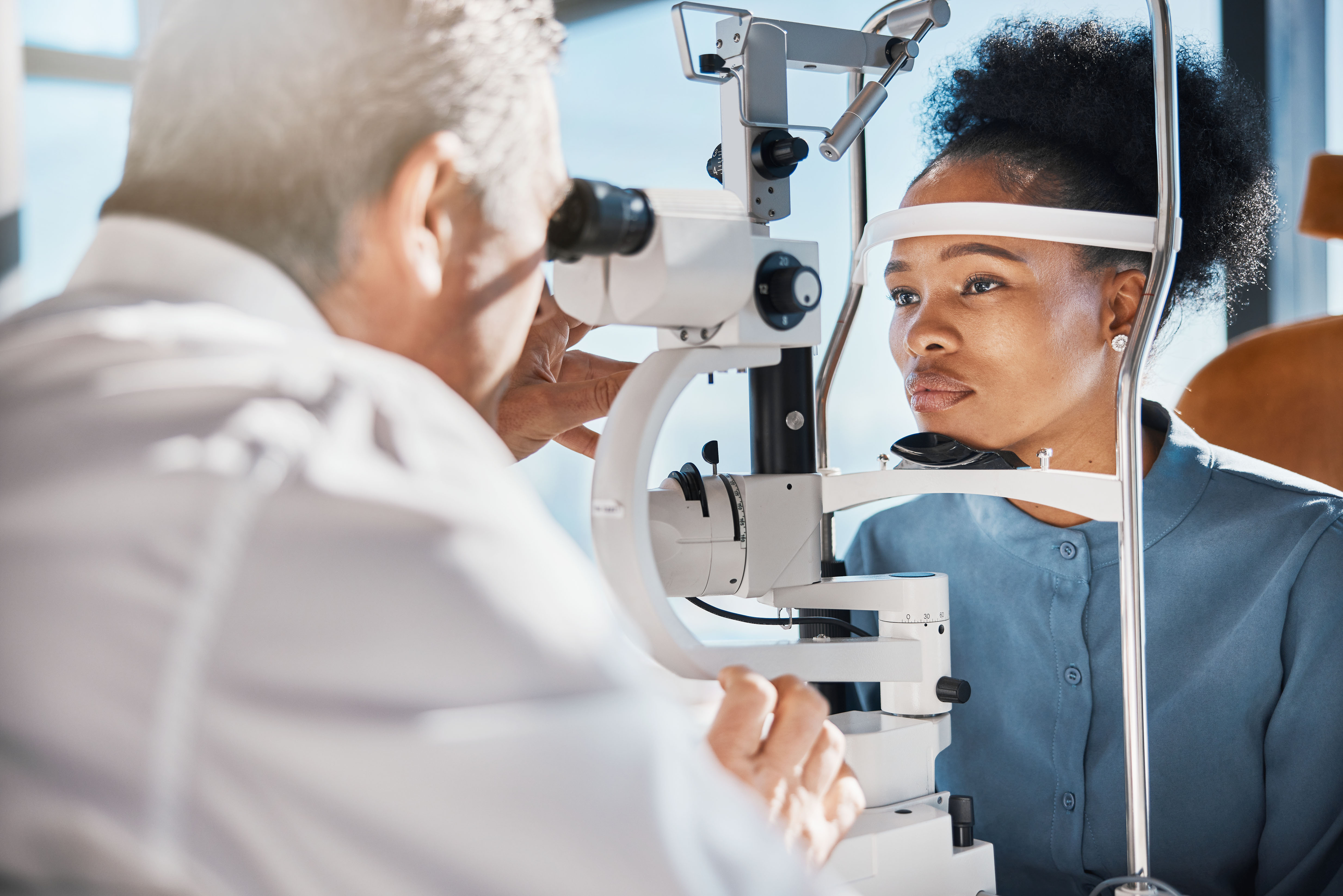 Help, eye exam or black woman consulting doctor for eyesight at optometrist or ophthalmologist. African customer testing vision with mature optician checking iris, glaucoma or retina visual health