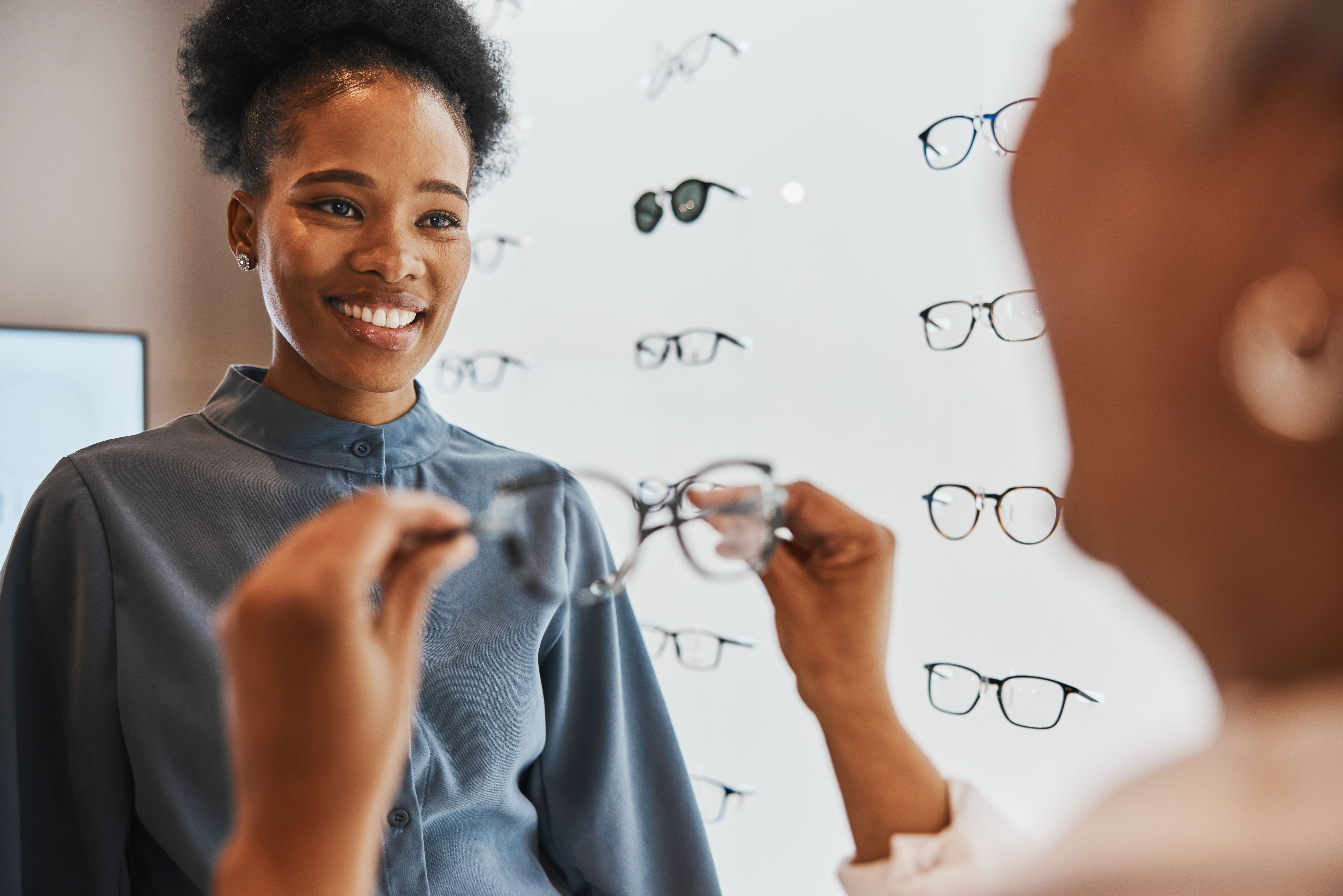 Glasses, black woman and retail customer with store worker and optician looking at lens. Eye consulting, smile and eyewear assessment in a frame shop for vision test and prescription exam for eyes